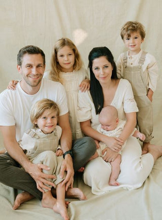 Family of five sitting together on a light-colored blanket