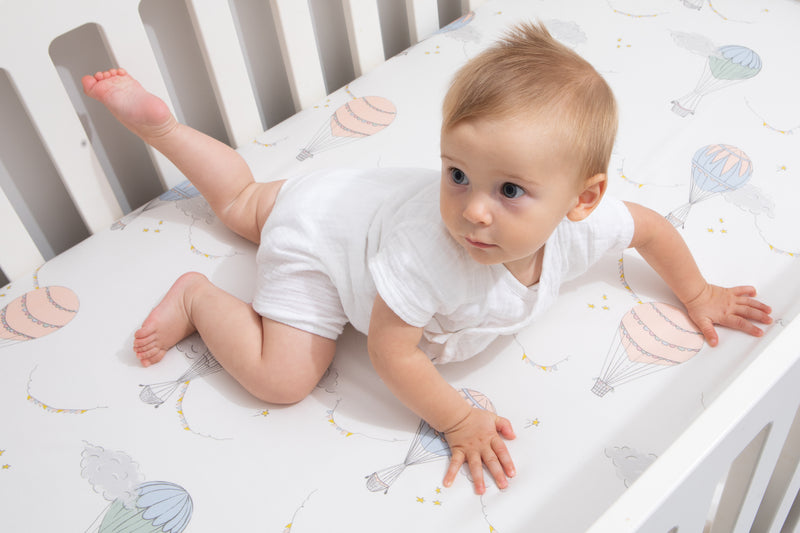 A baby crawling in its crib