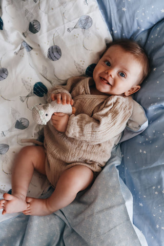 Baby playing with a small crocheted duck stuffed animal