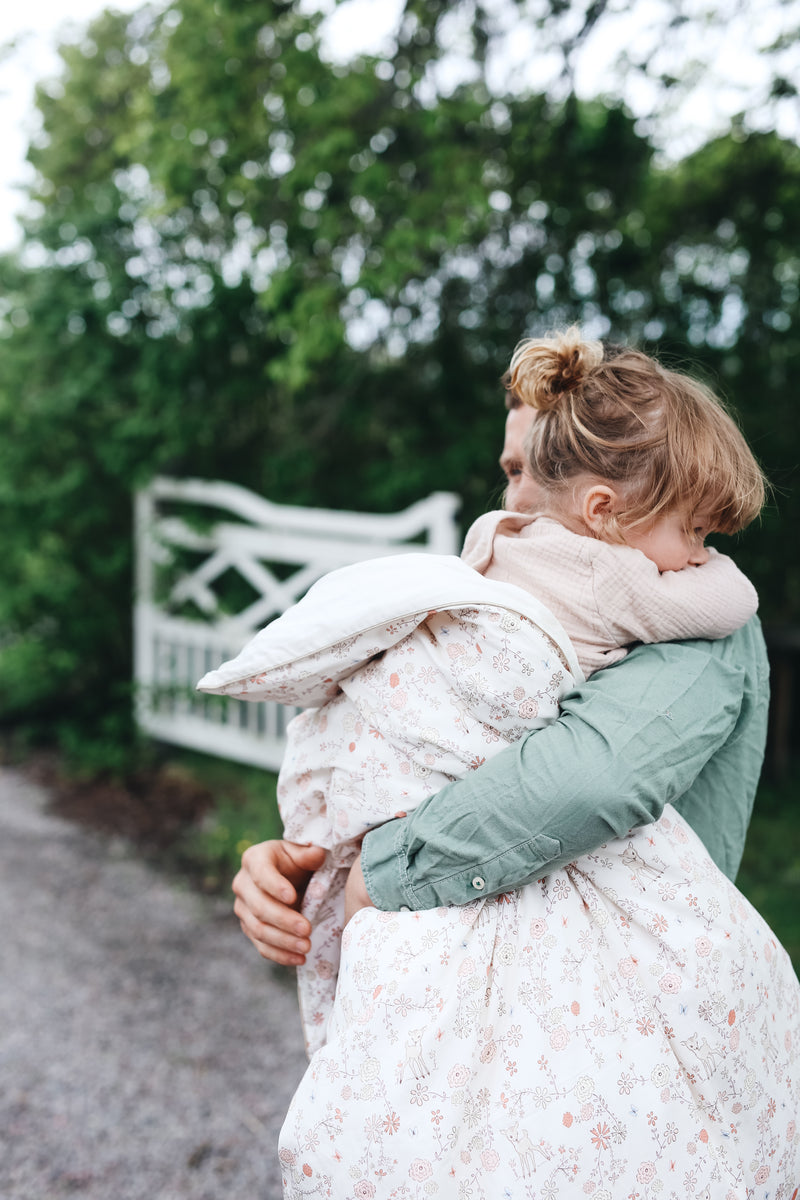 A father holding his daughter while she's wrapped in a Gooselings duvet