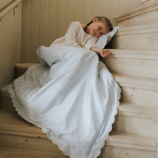 Scalloped Starlight Blue with Girl laying on Toddler Duvet with Pillow