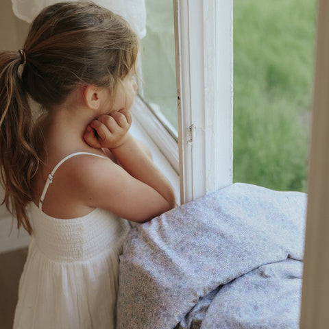 Girl looking at the window leaning on toddler duvet wildflower print