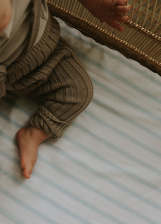 Striped crib sheet with baby sitting 