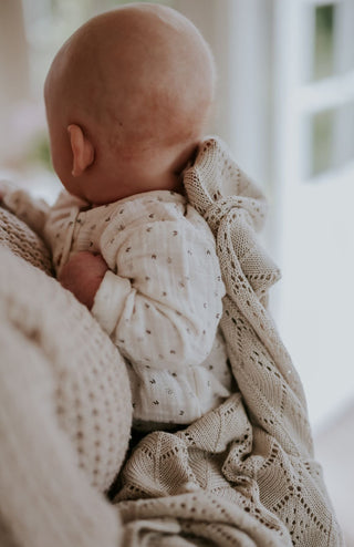 Baby wrapped in knit blanket in mother's arms