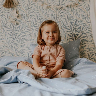 Child sitting on toddler bed smiling