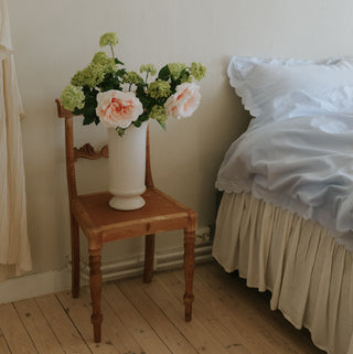 Picture of florals on a chair by a twin bed.