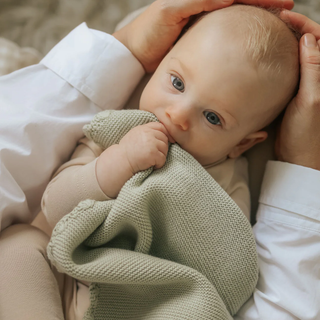 baby holding knit blanket