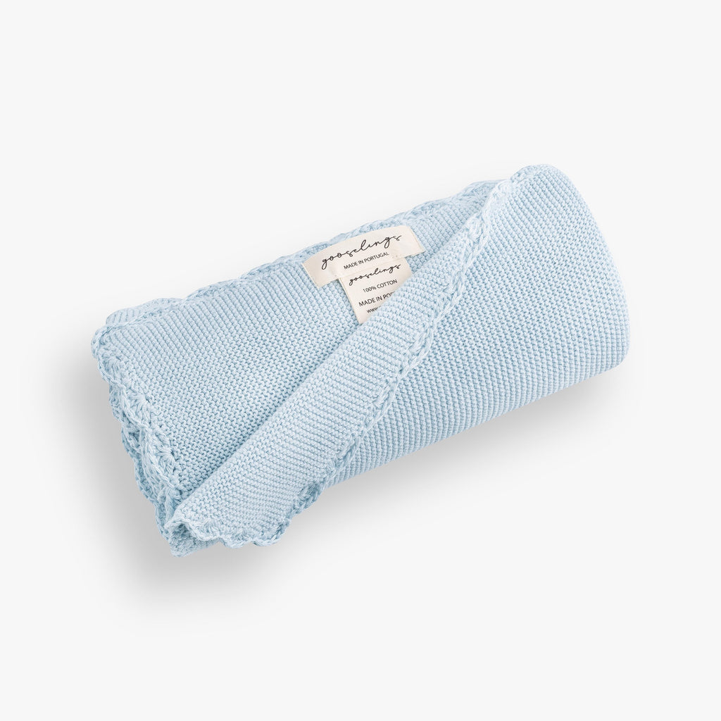 Cotton Knit Baby Blanket in Blue rolled up. The Gooselings label is shown for detail