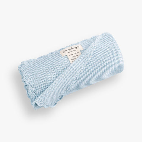 Cotton Knit Baby Blanket in Blue rolled up. The Gooselings label is shown for detail