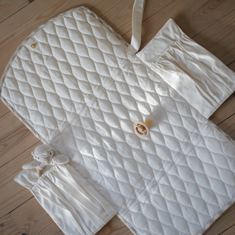 Portable Changing Pad in Beige Gingham opened up laying flat on the floor. Inside is in solid Ivory with two pocket details.
