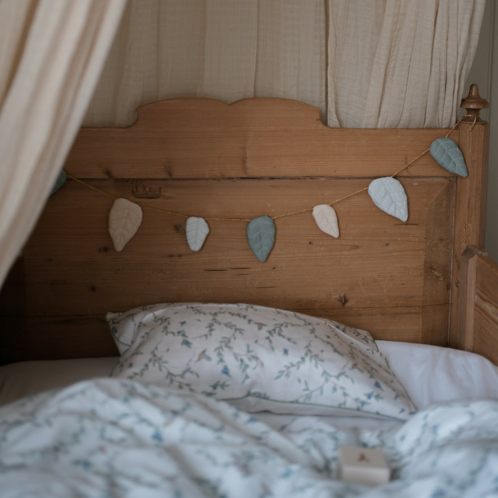 Secret Garden Garland hanging over bed on wooden bed frame