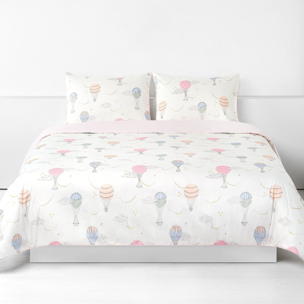 Touch The Sky Full/Queen Duvet Cover in the Pink Print displayed on bed. Shown with two standard size pillow cases in the same print.