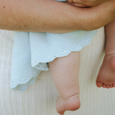Mom holding baby with blue knit blanket