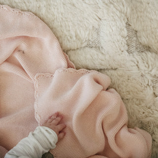 Cotton Knit Baby Blanket in Pink with a Baby's hand laying on top.