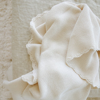 Cotton Knit Baby Blanket in Ivory laid out on rug to show the beautiful trim detail.