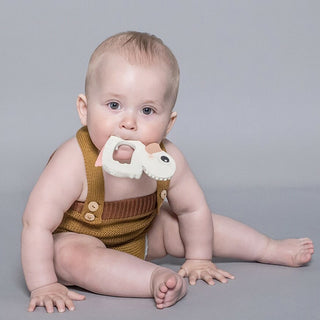 Gooseling Teether in  Marshmallow. Little boy playing on the floor with teether in his mouth.