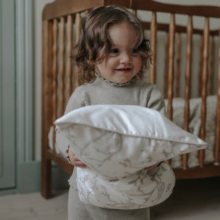Animal Parade Toddler Pillow in Ivory. Child holding pillow.