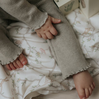 Animal Parade Baby Duvet in Ivory. Child sitting on top of duvet