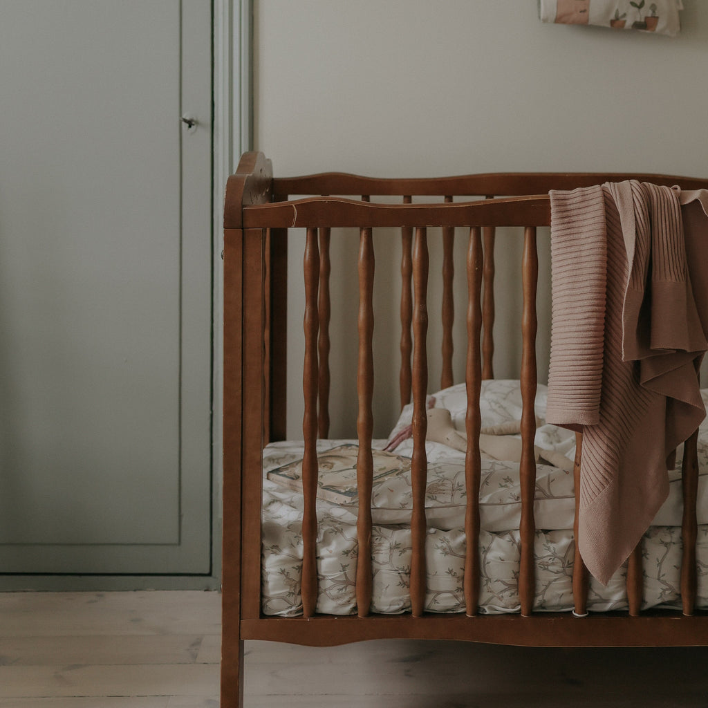 Animal Parade Crib Sheet in Ivory. Crib in room with  Baby Duvet, Crib Sheet and Pillow inside. Blanket hanging over crib.