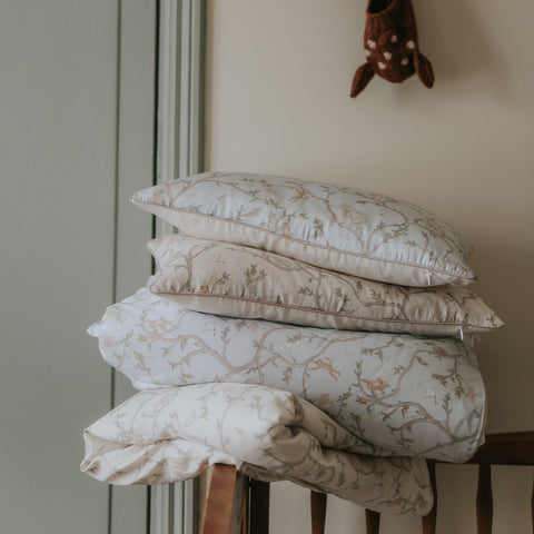 Animal Parade Toddler Pillow in Blue and Ivory. Pillows and Duvets are folded and piled on top of one another stacked on top of crib