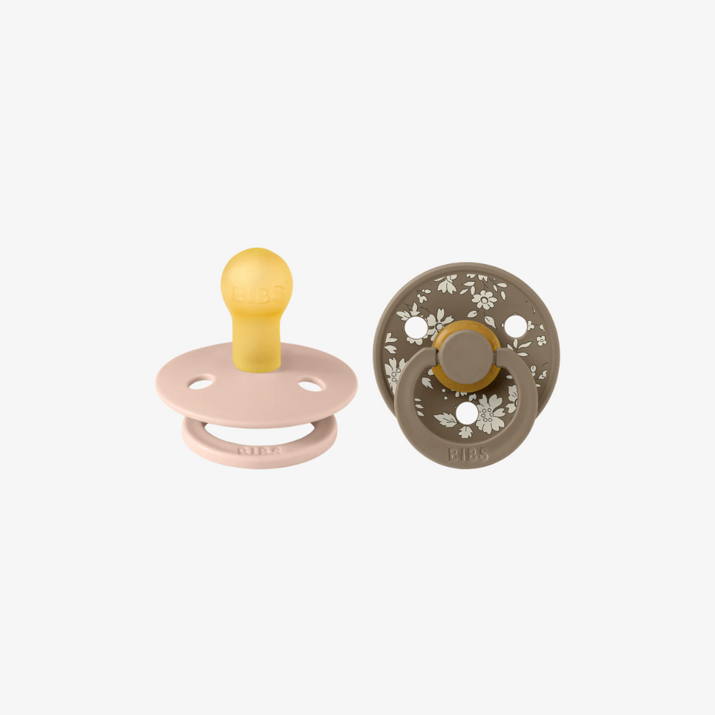 Two baby pacifiers on a white background, one pink and yellow, the other brown with floral pattern.