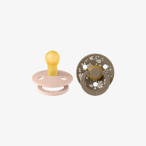 Two baby pacifiers on a white background, one pink and yellow, the other brown with floral pattern.