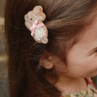 Close-up of a bunny-shaped hair clip with a pink bow in a child's hair.