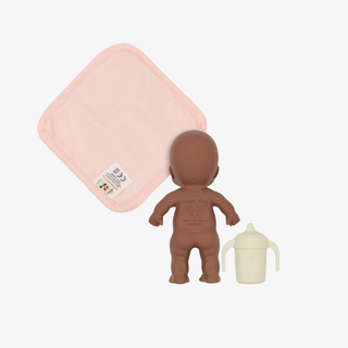 Baby doll, pink blanket, and cream bottle on a white background