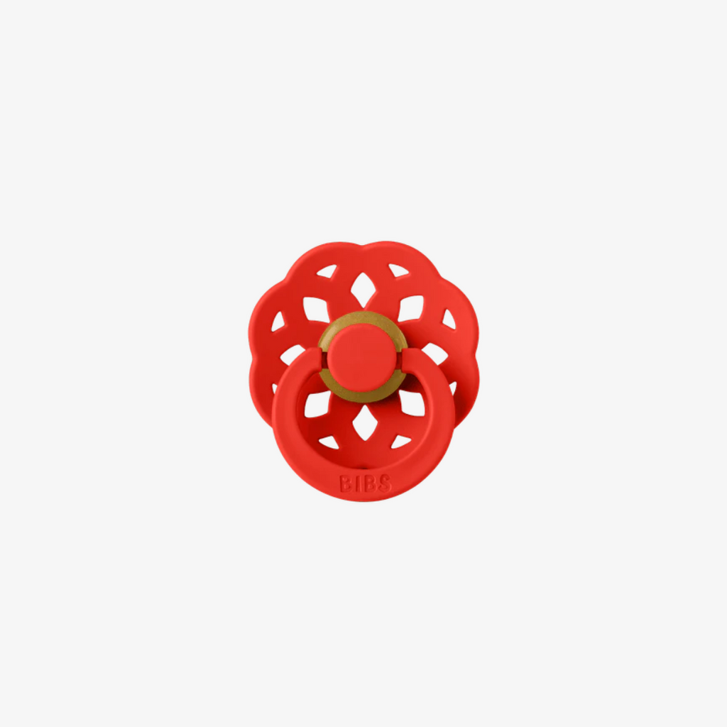 Red floral-patterned pacifier with a gold center on a white background