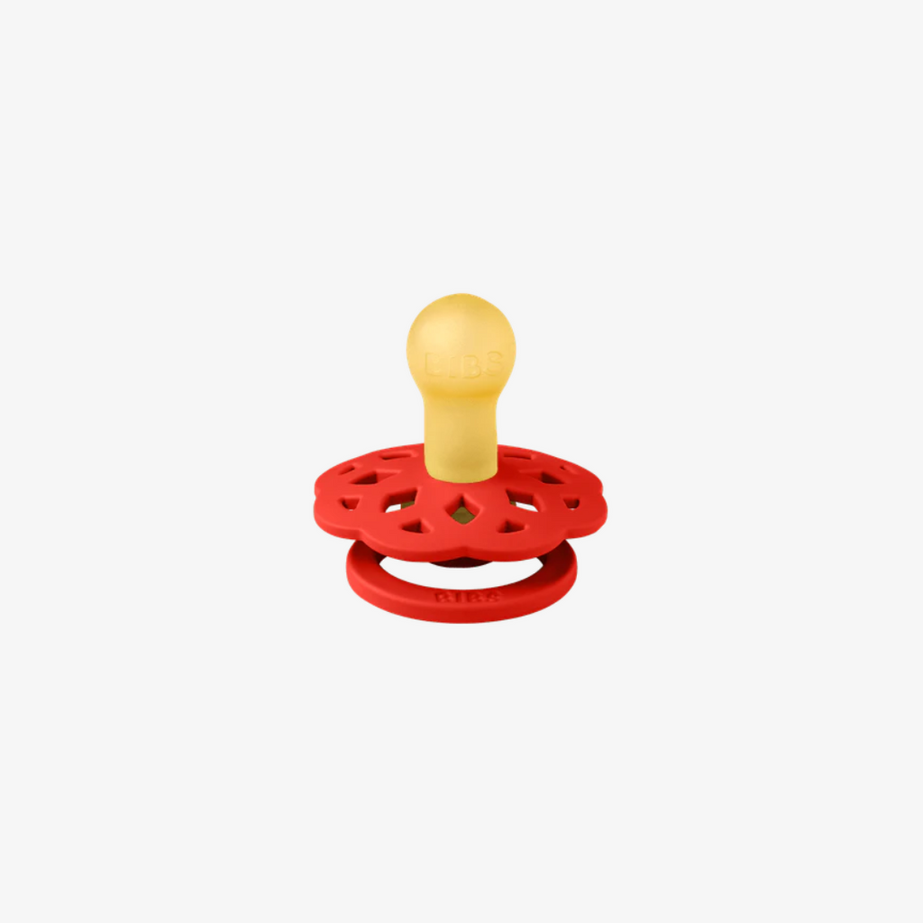 Red pacifier with a yellow center on a white background