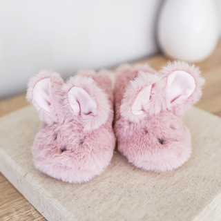 Pair of pink bunny slippers on a textured surface with a neutral background