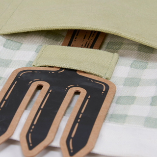 Close-up of a cardboard tool with a green strap on a checkered fabric background