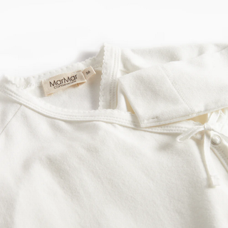 Close-up of a white baby garment with a brand label on a white background