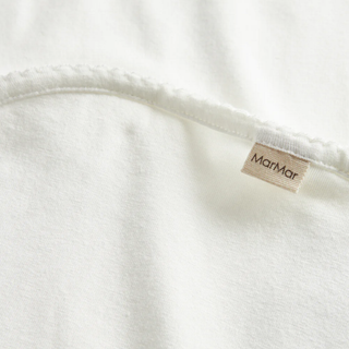 Close-up of a white fabric with a 'MarMar' label on a white background