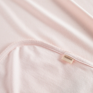 Close-up of a pink fabric with a brand label on a white background