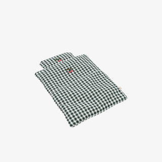 Green and white checkered fabric doll bed on a light gray background