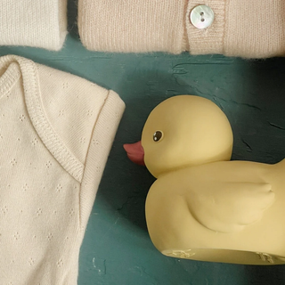 Yellow rubber duck on a green surface with a beige fabric background