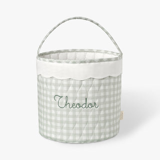 Fabric basket with a green gingham pattern and embroidered name on a white background