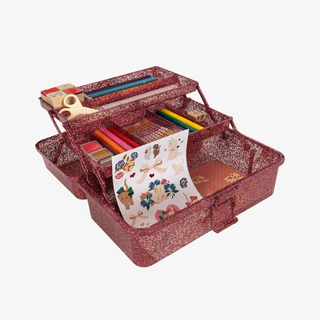 Red glittery art supply case with stationery items on a white background
