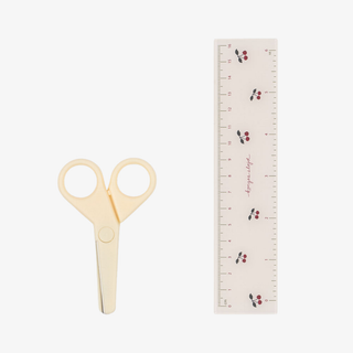 Pair of beige scissors next to a ruler on a white background
