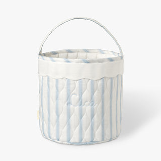 Blue ad white striped quilted basket with handle on while background.