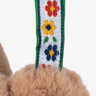 Close-up of a fluffy toy with a floral-patterned strap on a white background