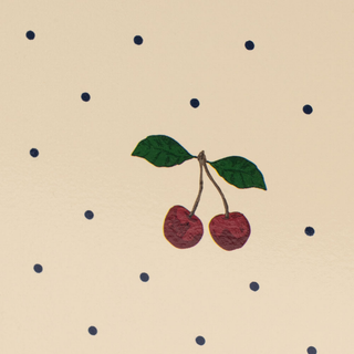 Illustration of two cherries with green leaves on a beige background with dark blue dots.