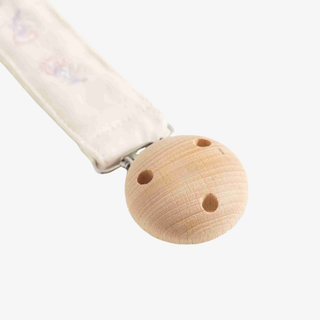 A close-up of a baby pacifier clip with a natural wood ball and a white fabric strap with a subtle pastel floral print, set against a solid light gray background.