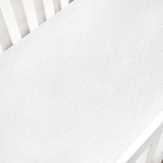 White crib sheet with blue polka dot pattern on a white crib
