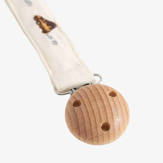 A close-up of a baby pacifier clip with a natural wood ball and a cream-colored fabric strap featuring a vehicle design.