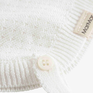 Close-up of a white ribbed knit garment corner with a small cream button and a beige fabric tag reading MarMor.