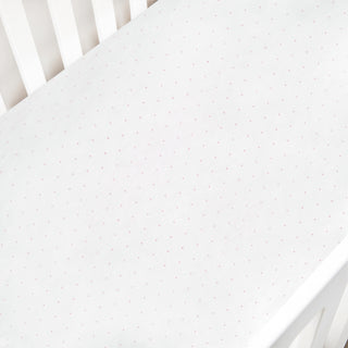 White crib sheet with pink polka dot pattern on a white crib
