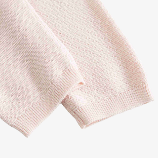 Close-up of a light pink knit pants, showing the ribbed cuff and fine knit texture against a plain light background.