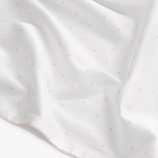 White fabric with pink polka dots on a white background